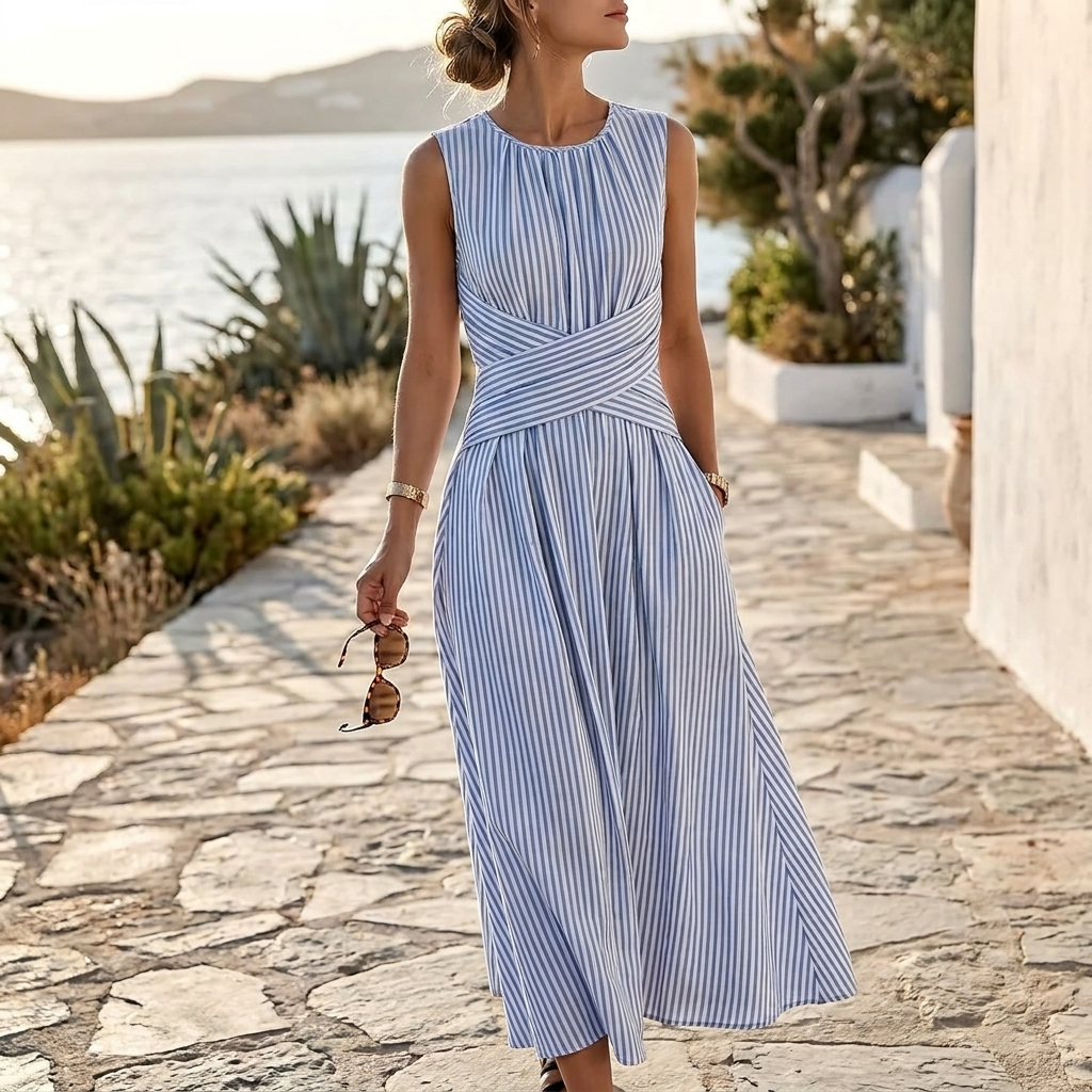 Woman in a blue and white striped dress walking on a stone path with a scenic background.