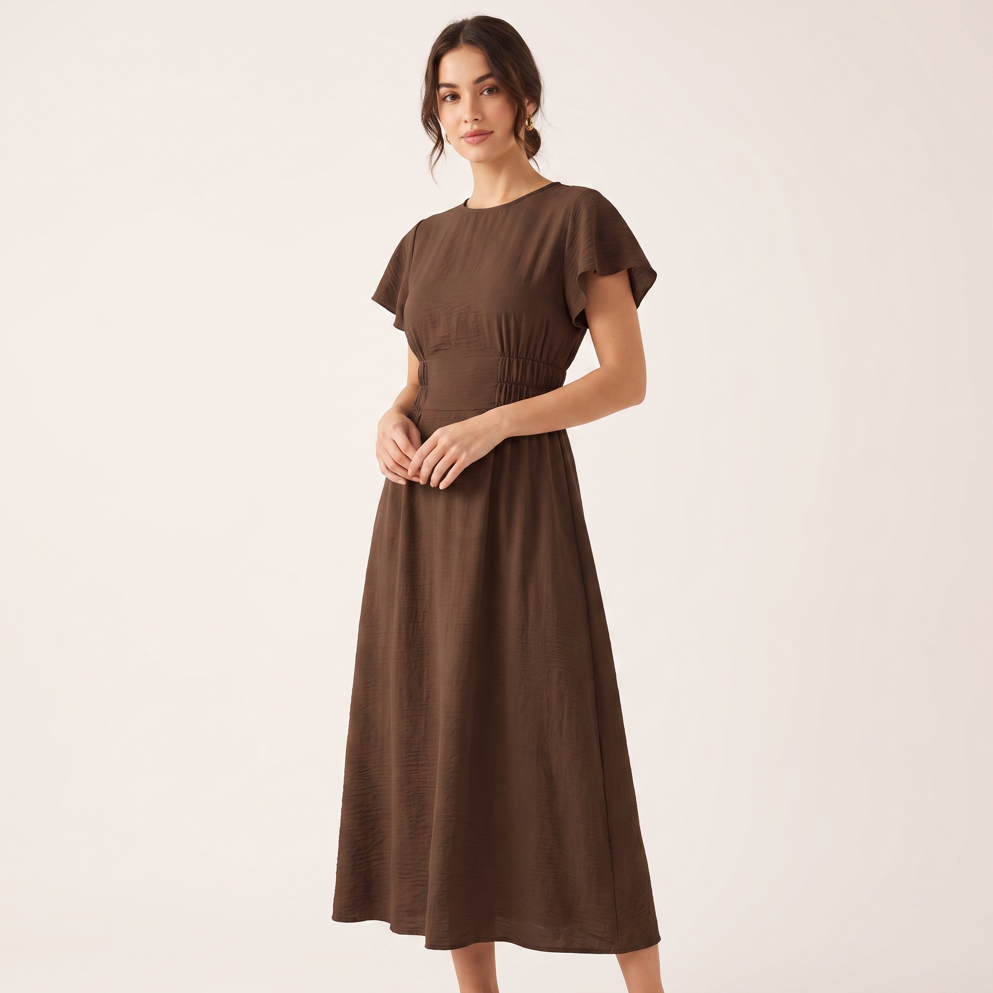 Woman wearing a brown dress on a plain background