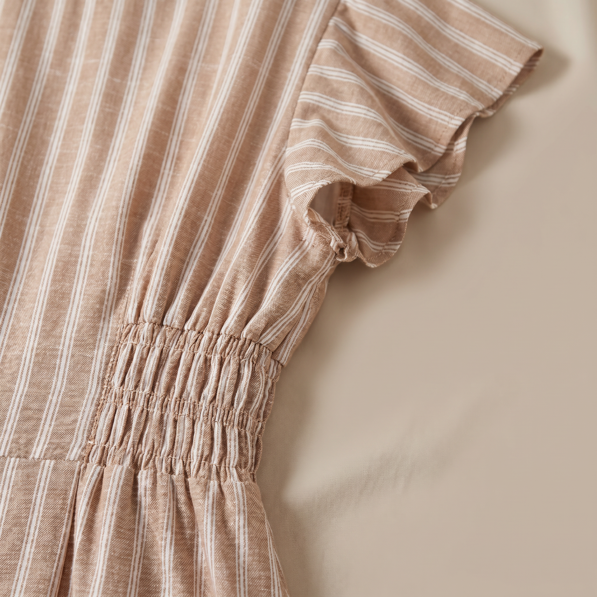 Close-up of a brown and white striped dress on a beige background