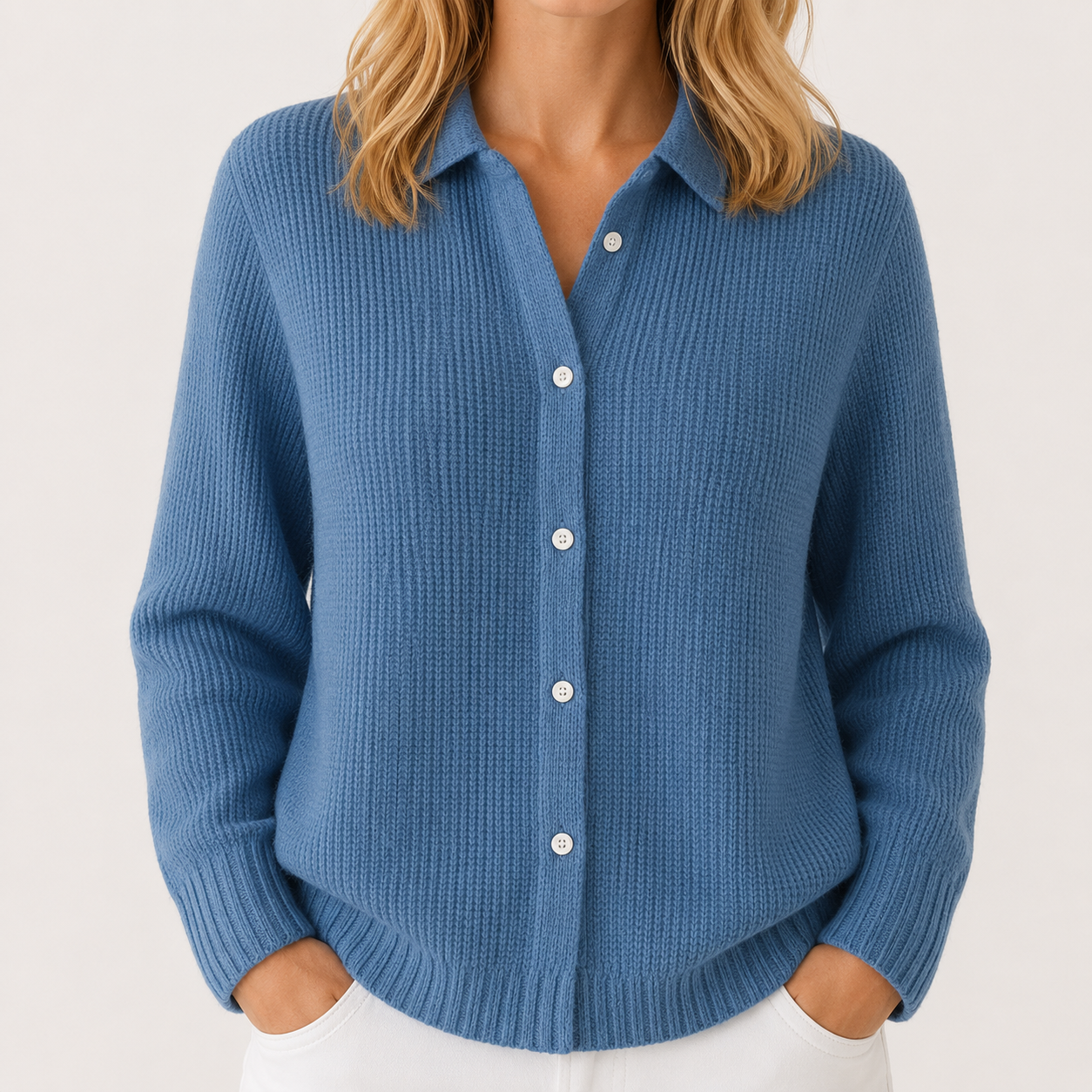 A woman wearing a blue ribbed knit button-up cardigan sweater with white buttons, shown from the neck down against a light off-white background.