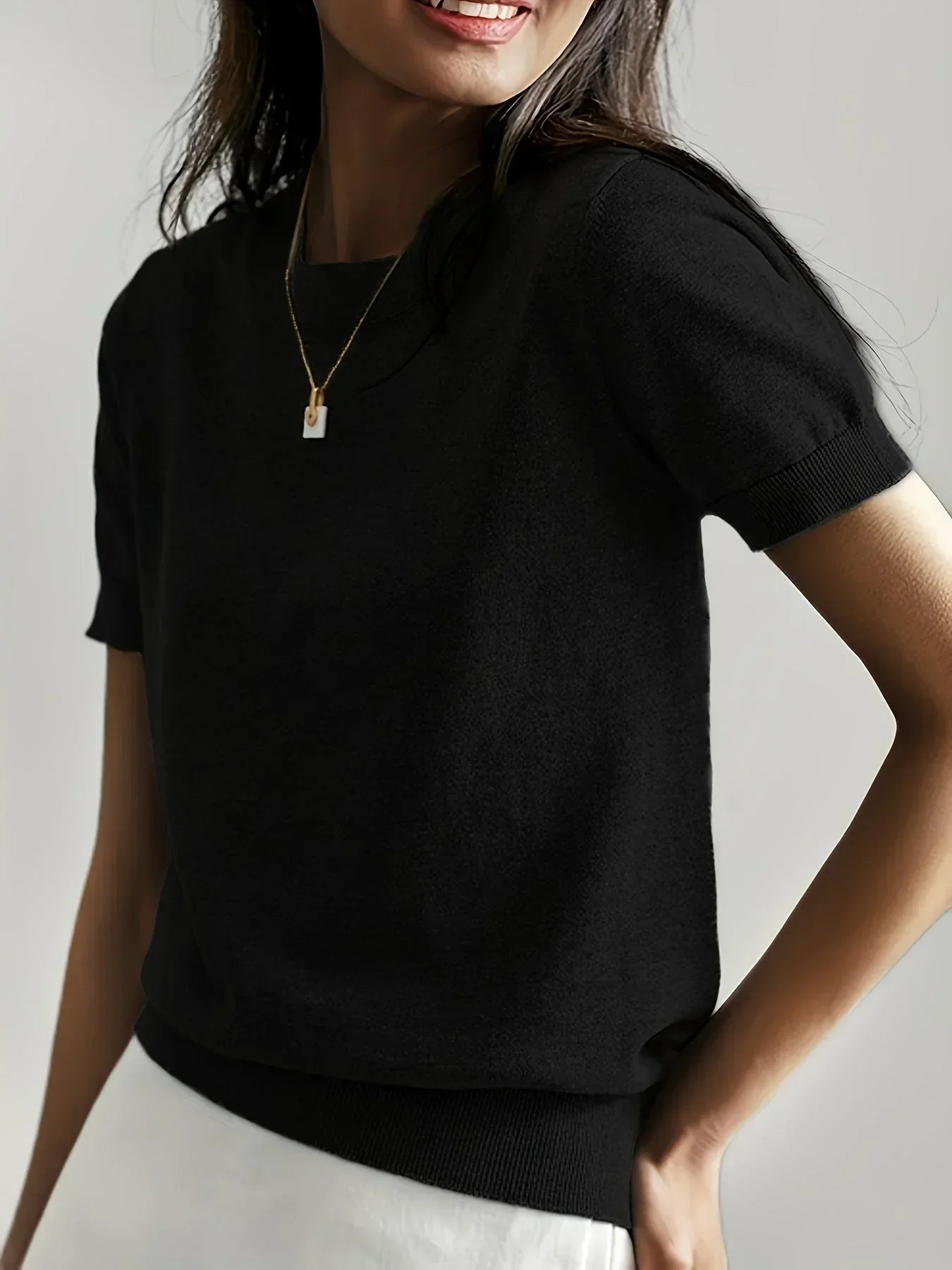 Black short-sleeve fine knit sweater with a crew neck and ribbed trim detail on the sleeves and hem.