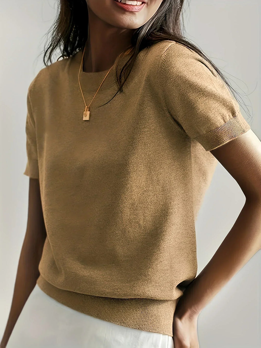 Khaki fine knit short sleeve sweater with a crew neck and ribbed trim, worn with a gold pendant necklace.