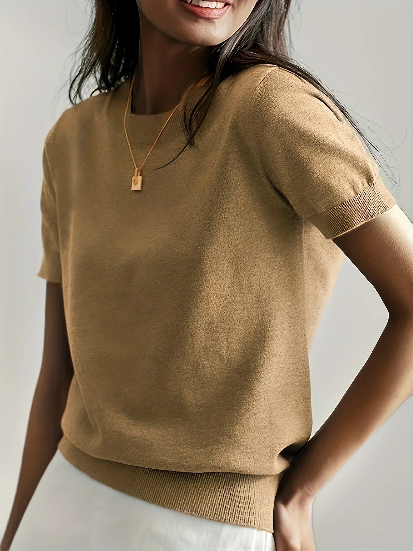 Khaki fine knit short sleeve sweater with a crew neck and ribbed trim, worn with a gold pendant necklace.