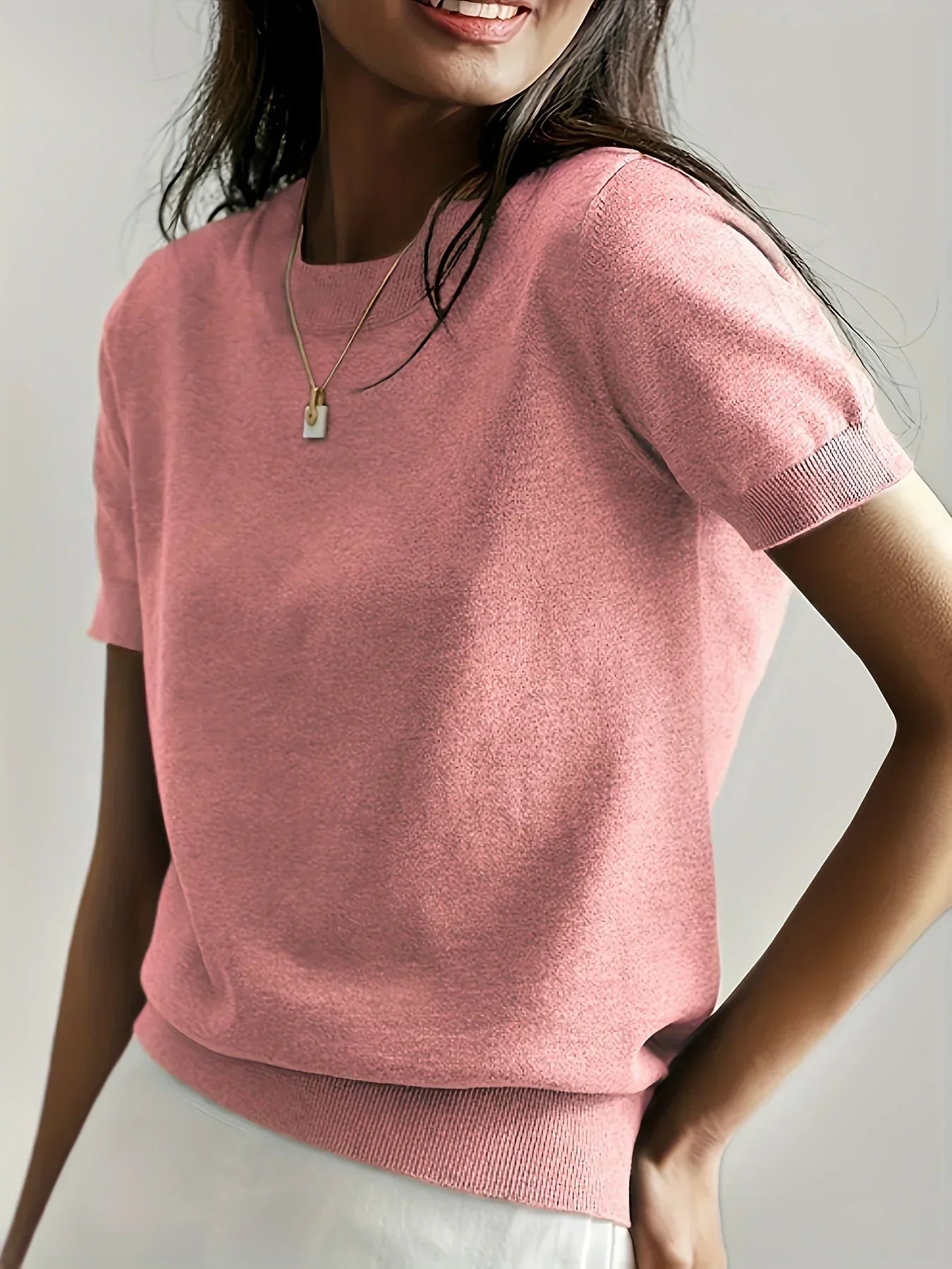 Pink fine knit short sleeve sweater with a crew neckline and ribbed trim details.