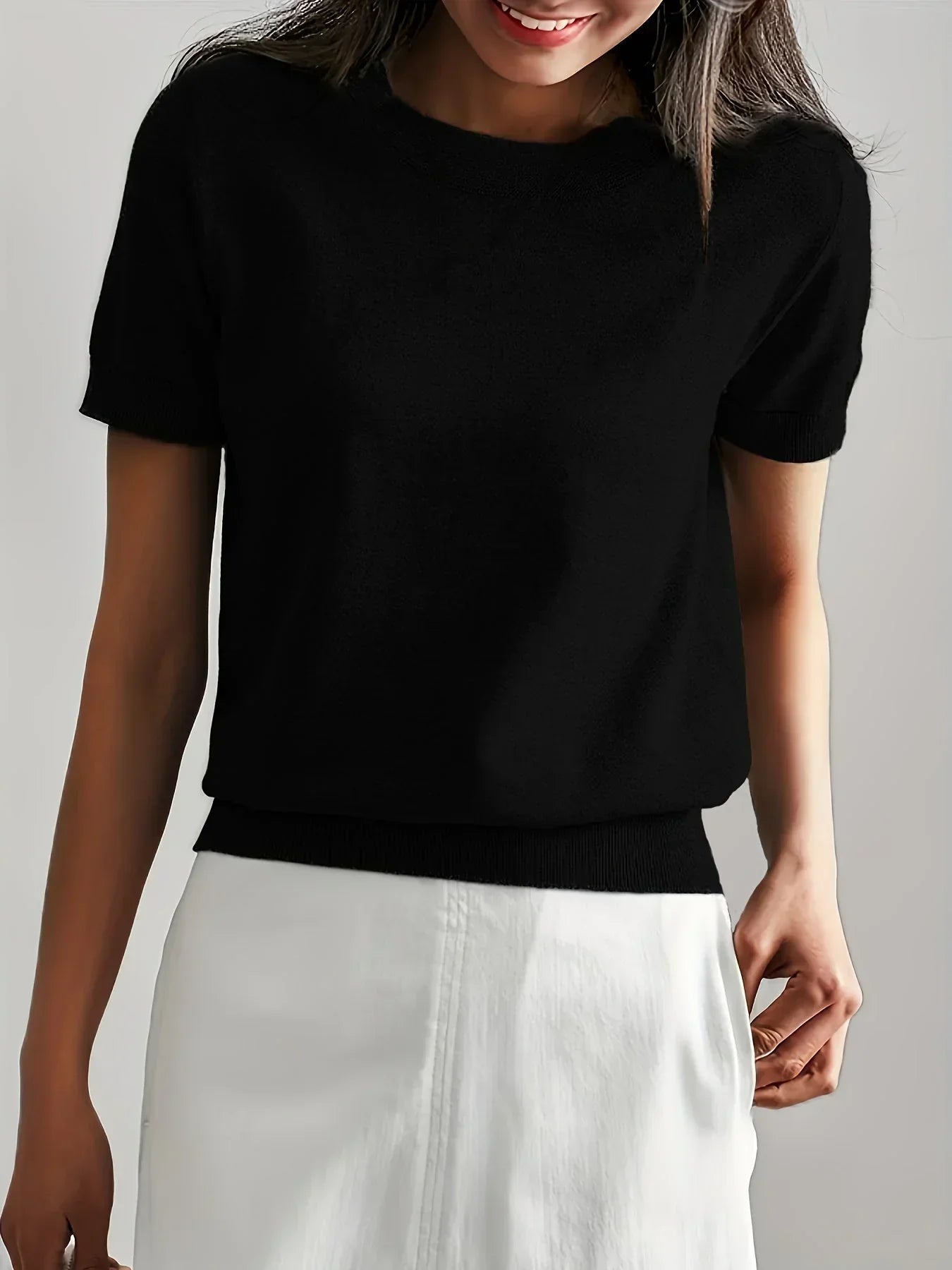 Black short-sleeve fine knit sweater with a crew neck and ribbed trim, styled with a white skirt.
