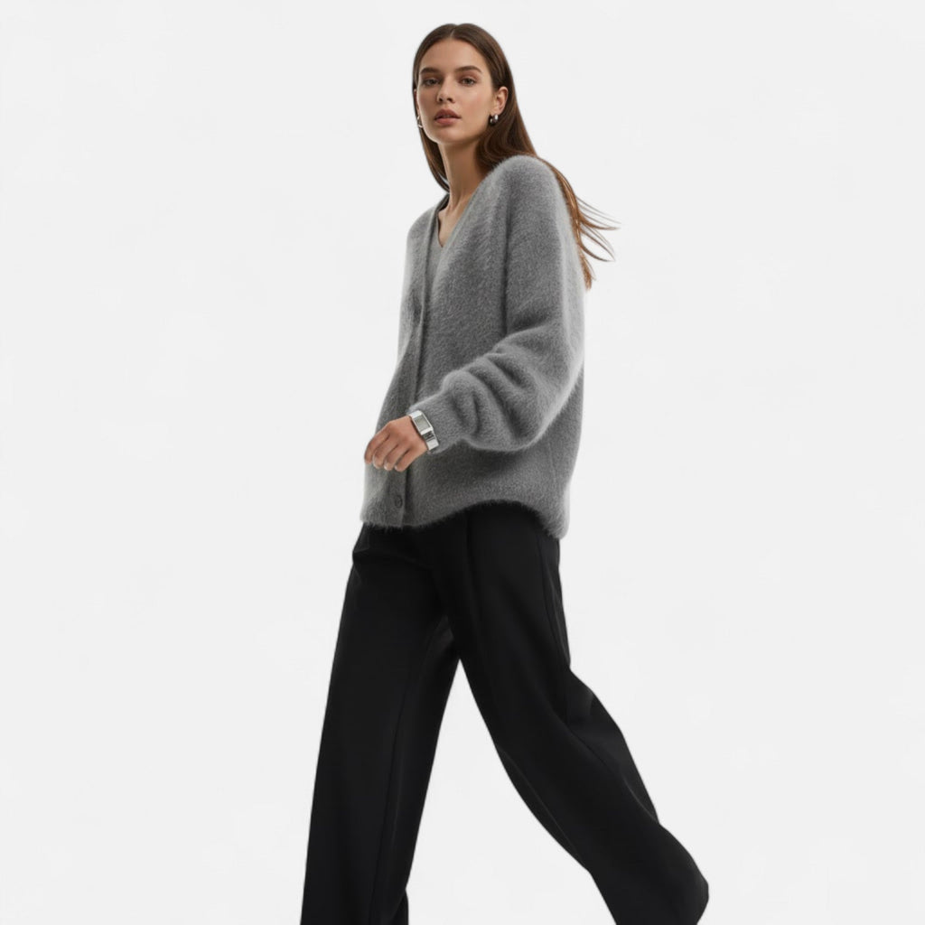Woman wearing a grey loose-fit V-neck buttoned knit cardigan paired with black trousers.