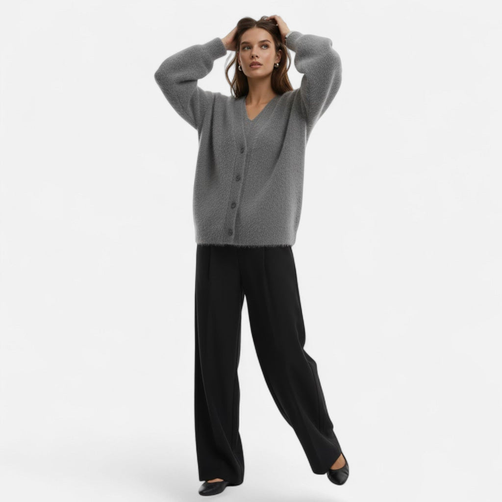 Woman wearing a grey loose-fit V-neck buttoned knit cardigan paired with black wide-leg trousers.