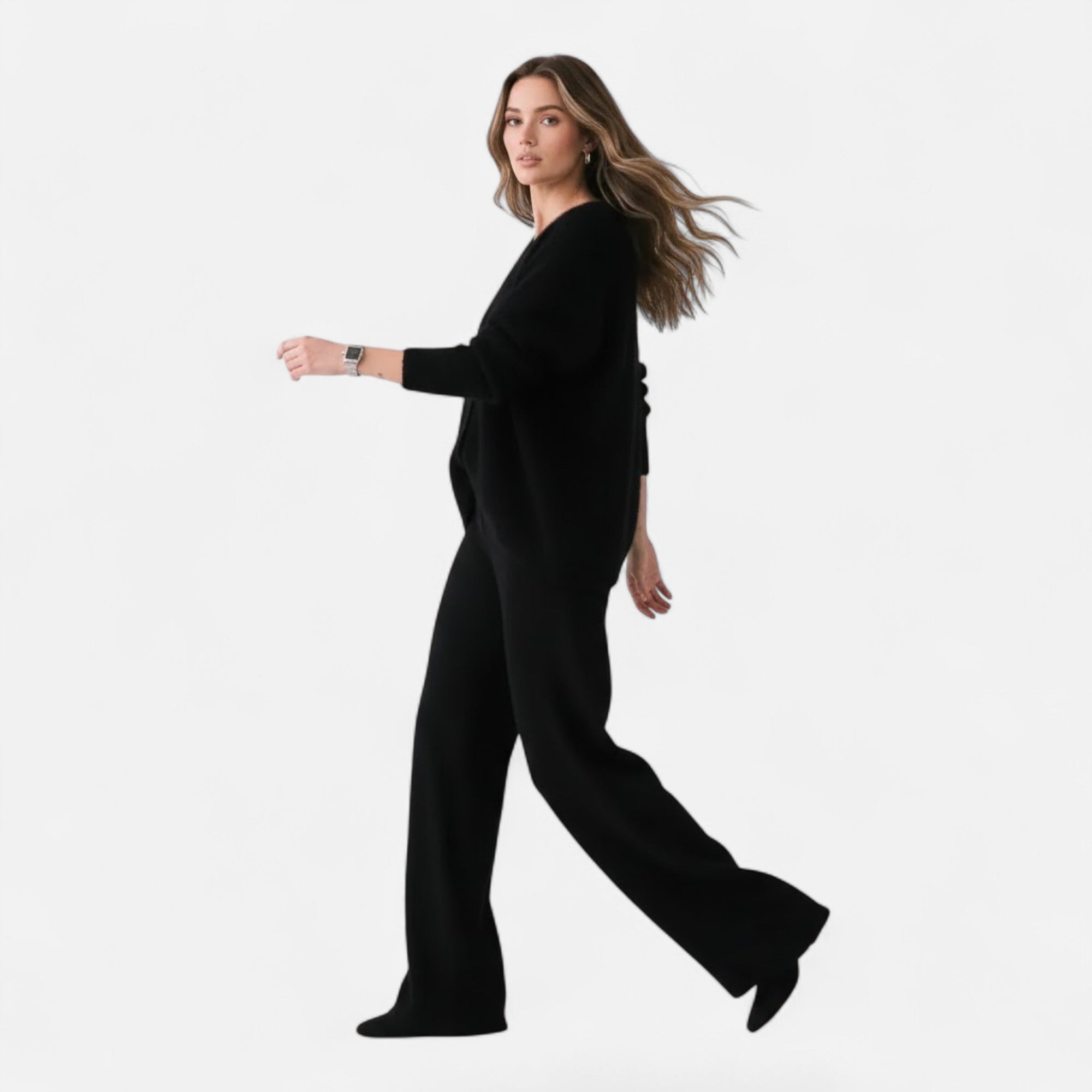 Woman wearing a black loose-fit V-neck buttoned knit cardigan and matching wide-leg trousers against a white background.