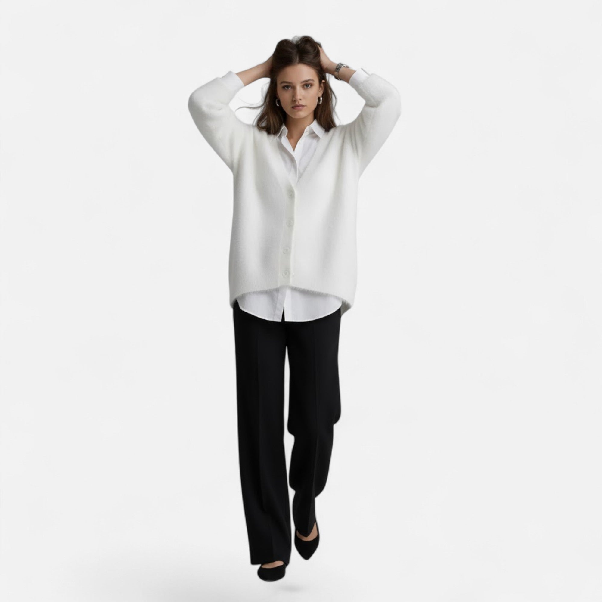 Woman wearing a loose, white V-neck buttoned knit cardigan over a white shirt and black trousers.