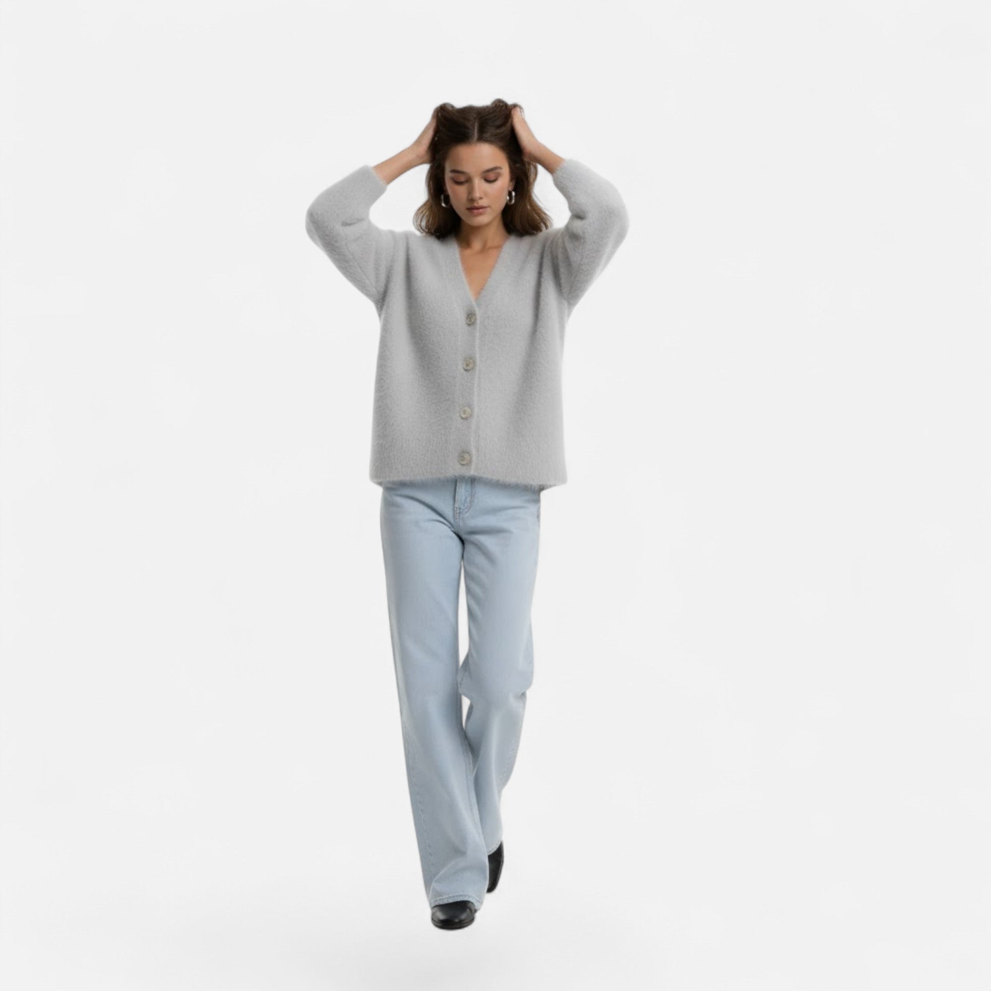 Woman wearing a soft, light grey V-neck buttoned knit cardigan paired with light-wash denim jeans.