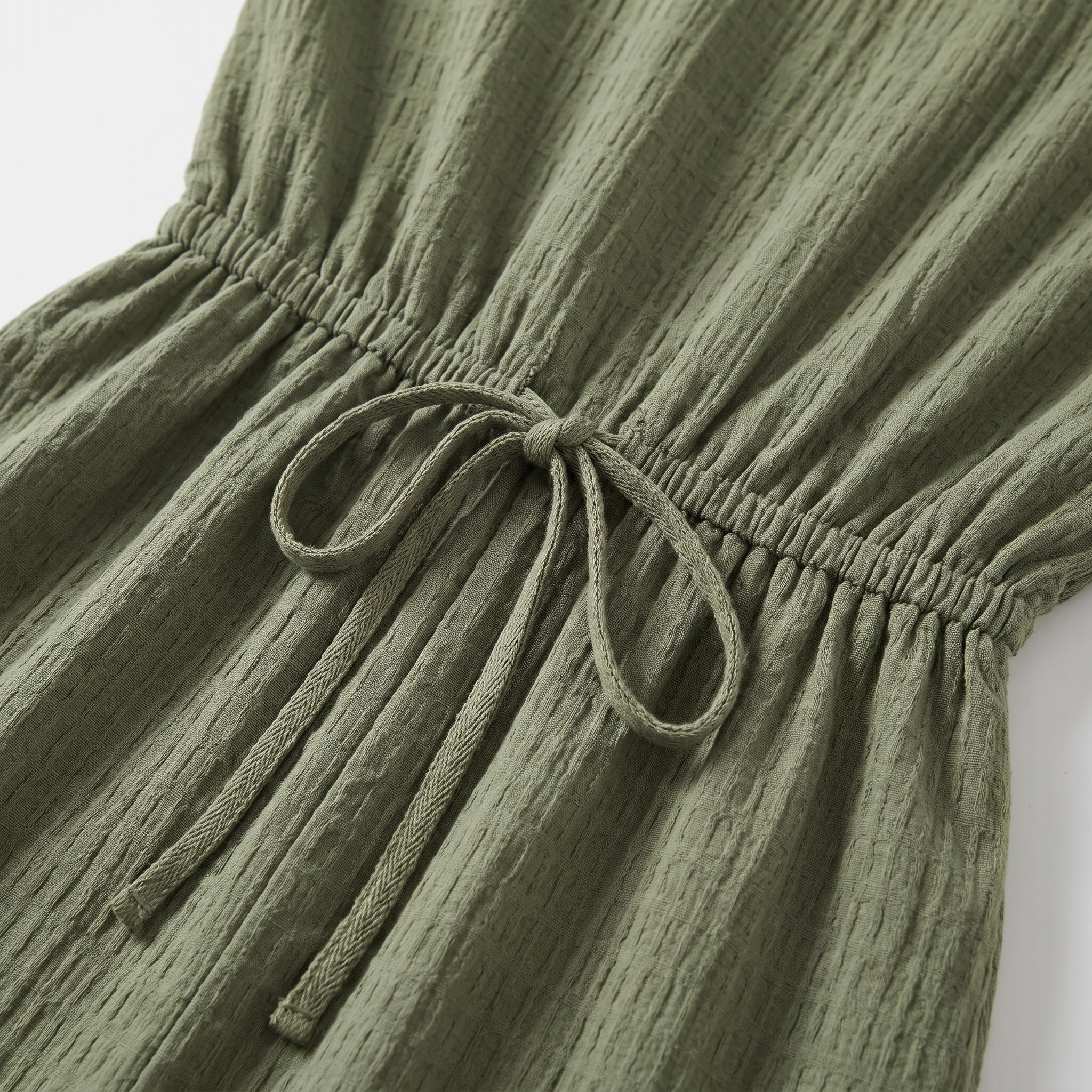 Close-up of a green dress with a tie detail on a white background