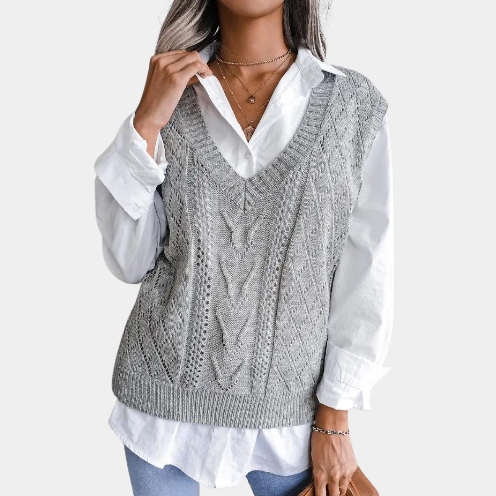 Grey openwork knit sweater vest with a deep V-neck, ribbed hem, and extended shoulders layered over a white shirt.