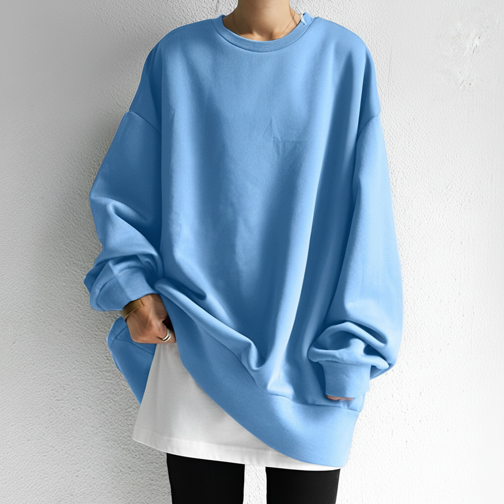 Light blue oversized crew neck sweatshirt with dropped shoulders and ribbed trims, worn over a white layer and black leggings.