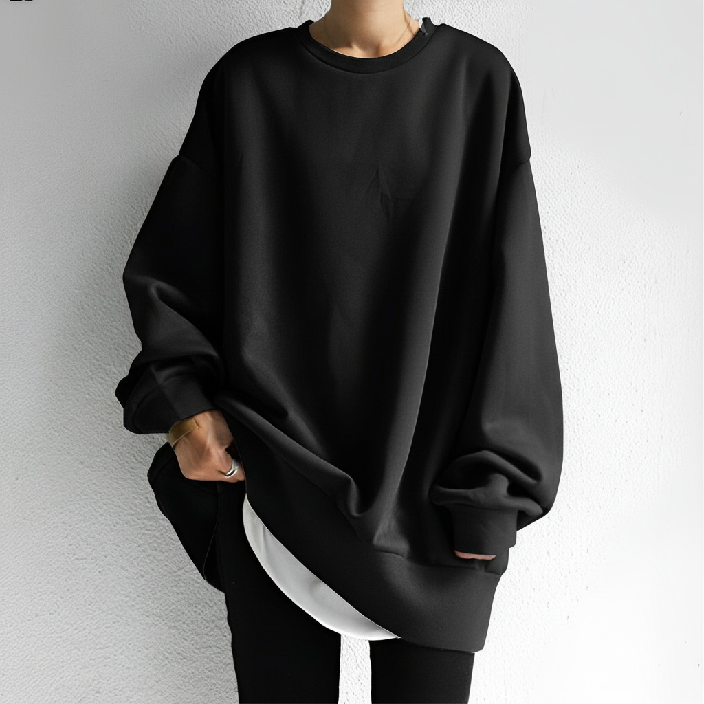 Oversized black crew neck sweatshirt with dropped shoulders, long sleeves, and a ribbed hem layered over a white shirt.