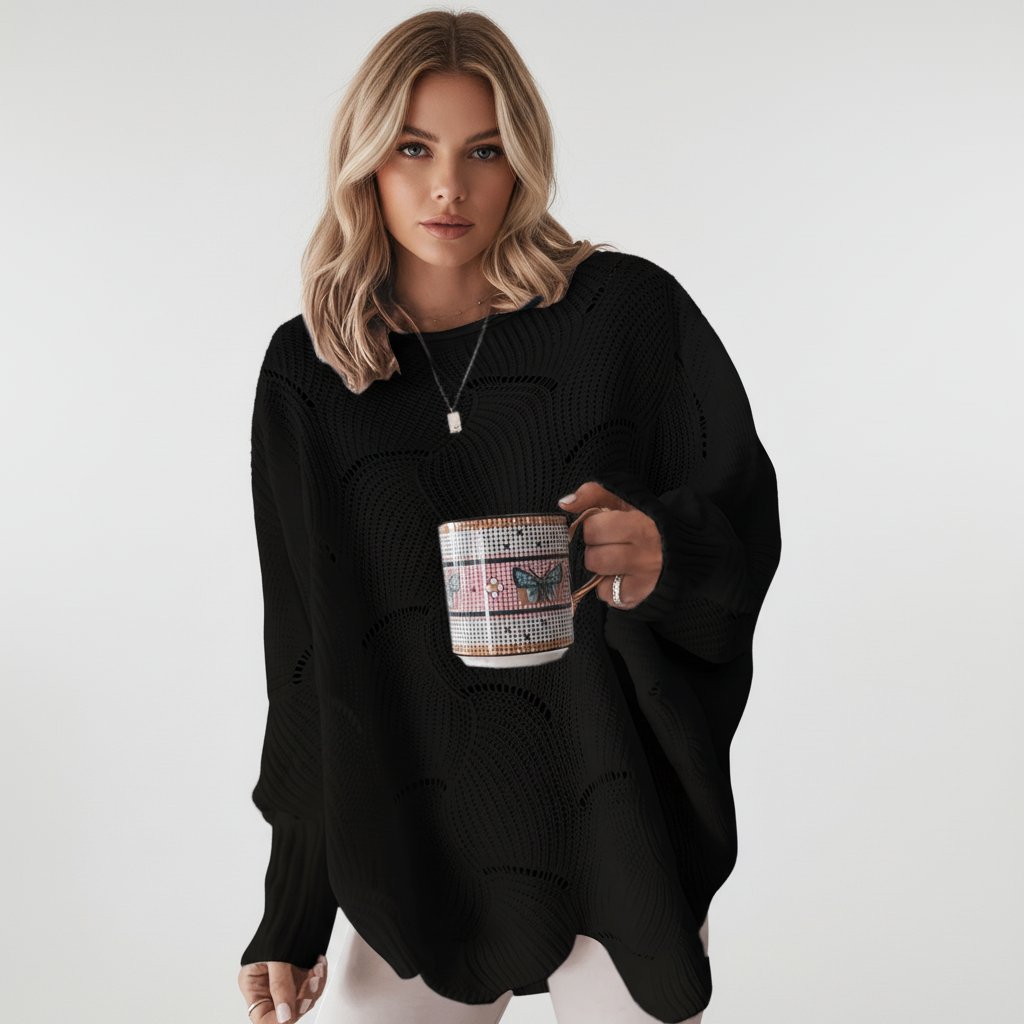 Woman wearing a black oversized open-knit sweater with a crew neck, long ribbed sleeves, and an asymmetric hem.