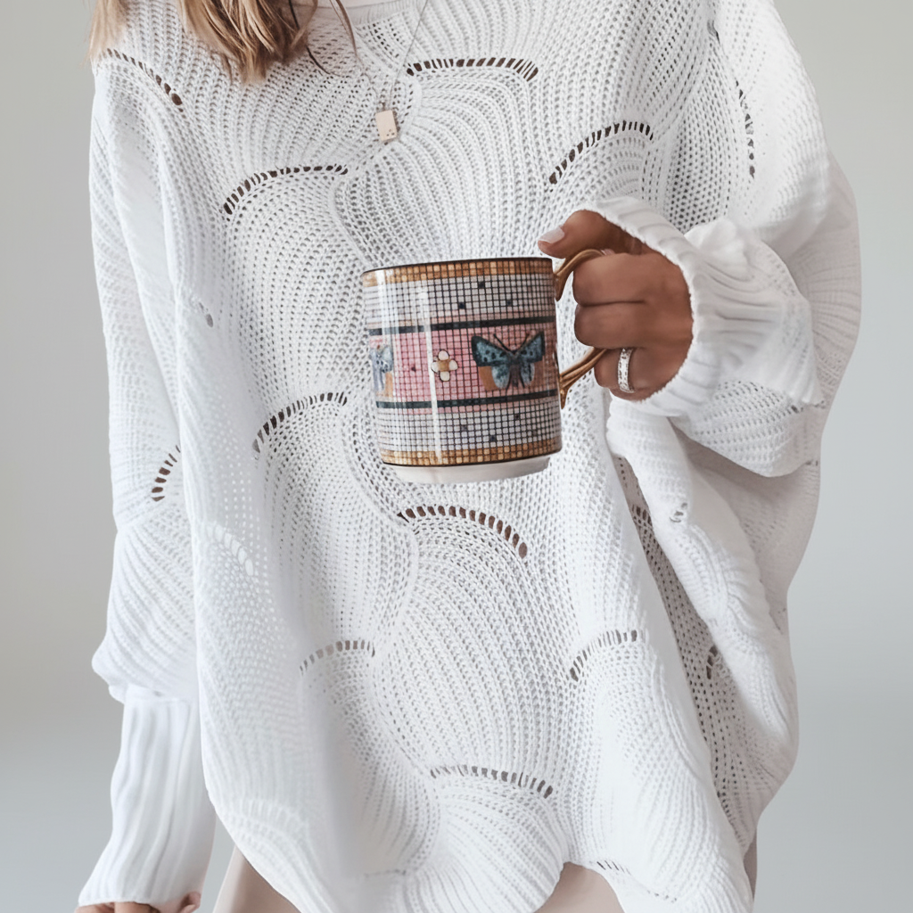 Oversized white open-knit sweater with a crew neck, long ribbed sleeves, and a draped asymmetric hem.