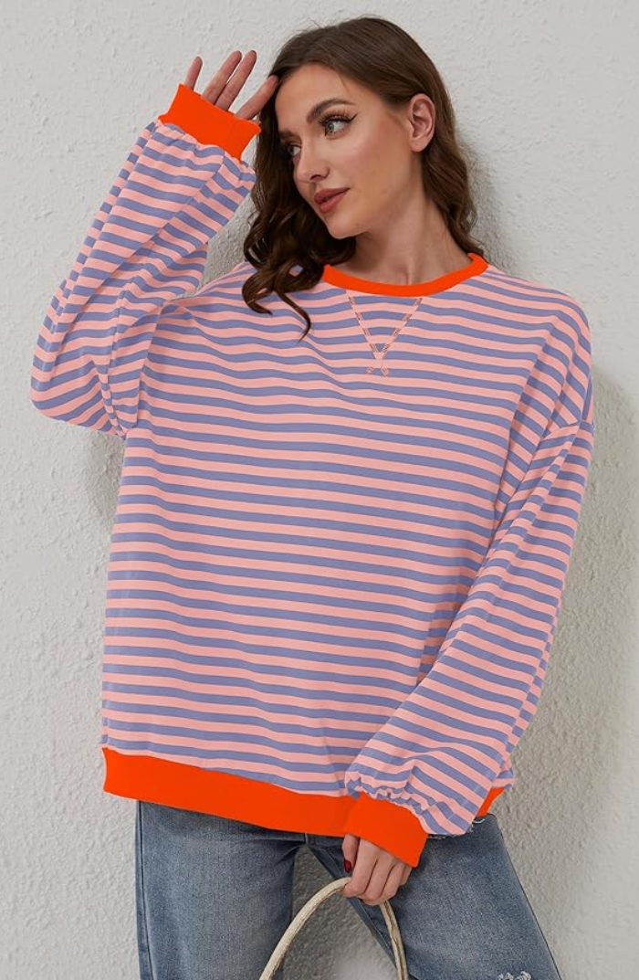 Oversized striped sweatshirt with purple and pink stripes, bright orange ribbed trim, and voluminous balloon sleeves.