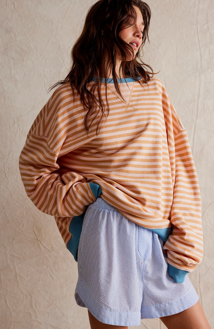 Oversized peach and white striped sweatshirt with blue balloon sleeves and ribbed trim worn with blue shorts.