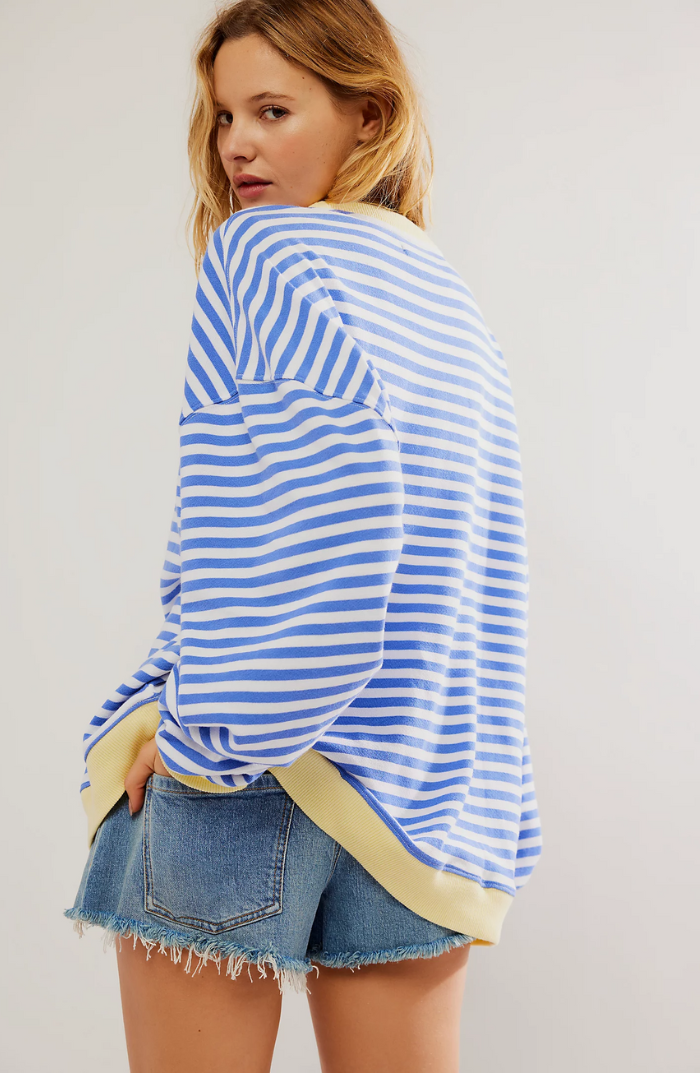 Oversized blue and white striped sweatshirt with balloon sleeves and yellow ribbed trim paired with denim shorts.