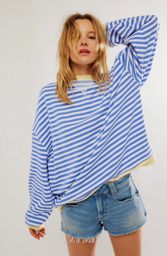 Oversized blue and white striped sweatshirt with balloon sleeves and yellow ribbed trim paired with denim shorts.