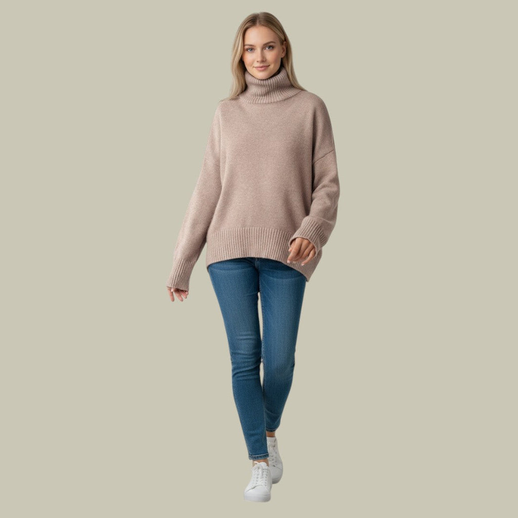 Beige oversized turtleneck sweater with ribbed knit details, dropped shoulders, and long sleeves worn with blue jeans.