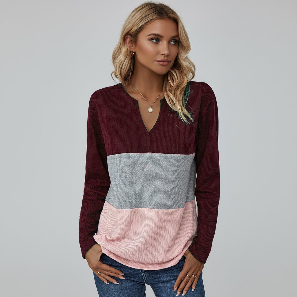 Woman wearing a wine red, grey, and pink color-blocked long-sleeve sweater with a split V-neckline.