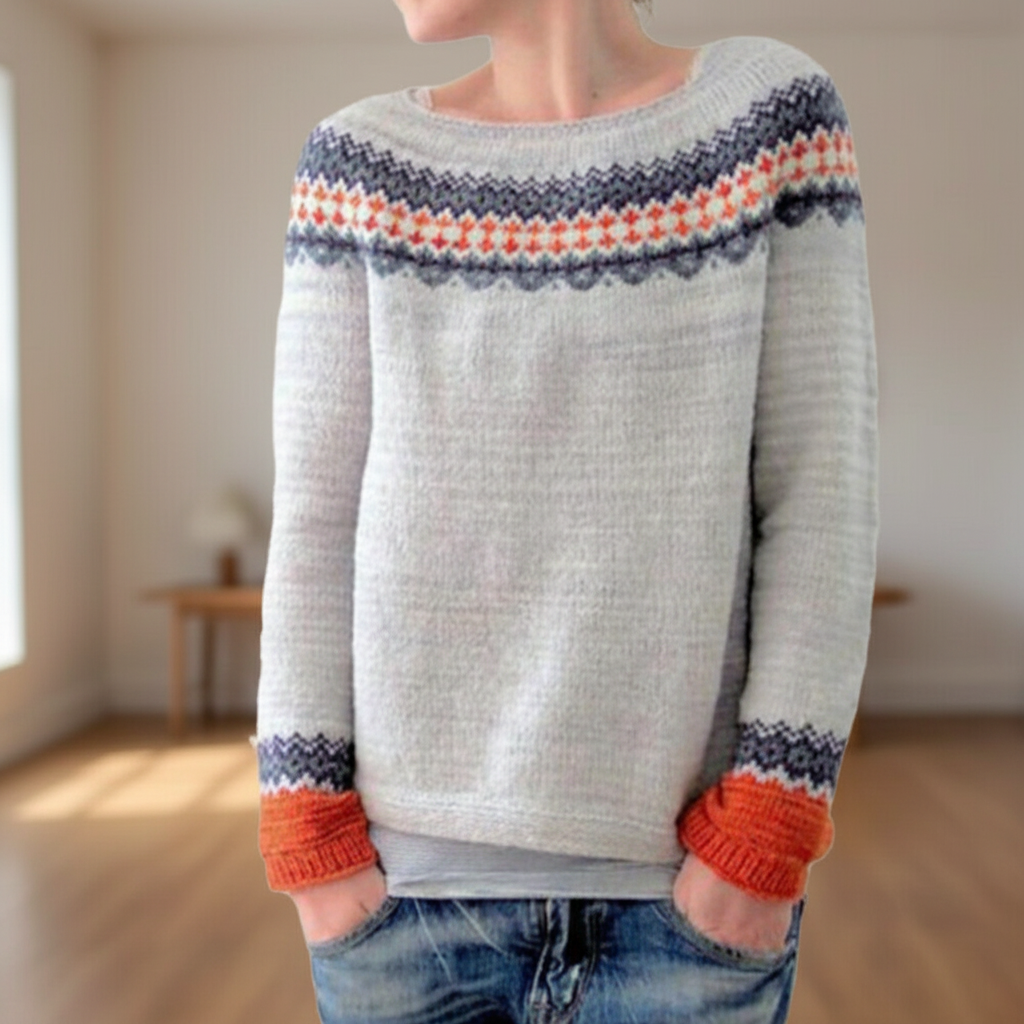 Light grey fitted sweater with a round neckline, patterned yoke, and long sleeves featuring orange ribbed cuffs.