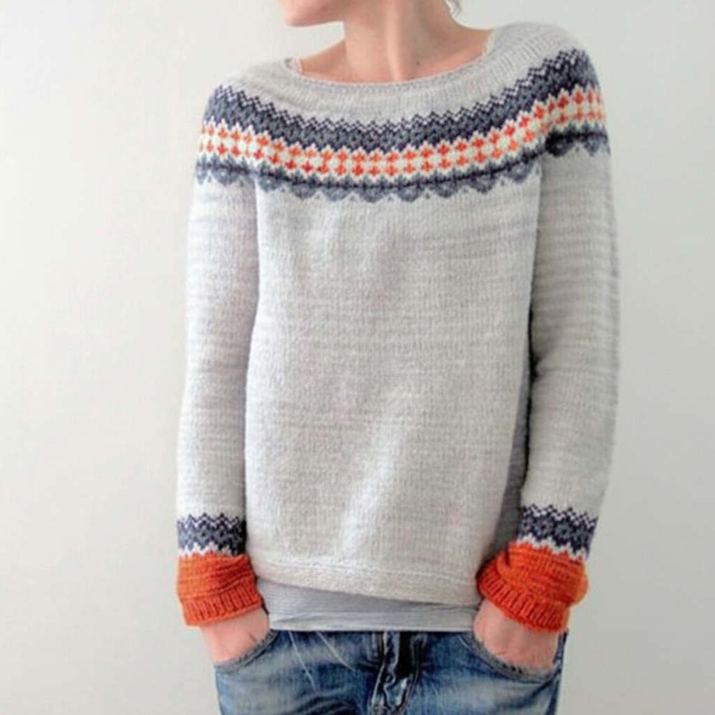 Light grey fitted sweater with a round neckline, featuring a colorful geometric print yoke and ribbed orange cuffs.