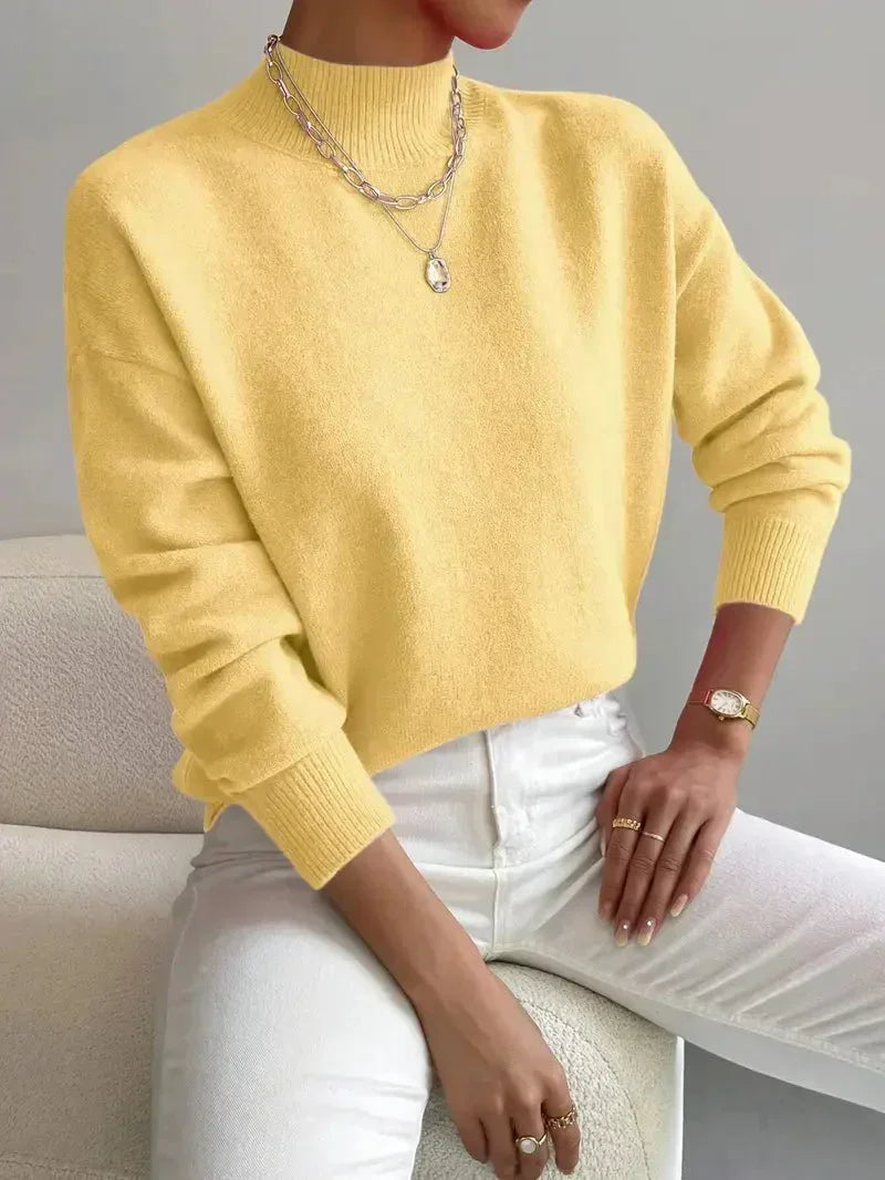 Yellow relaxed mock neck sweater in a smooth knit with long sleeves and ribbed trim, styled with white jeans.