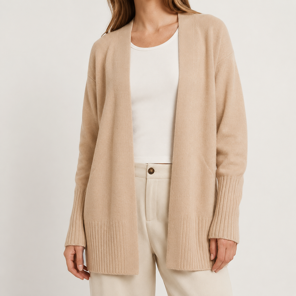 A woman wearing a light beige open-front knit cardigan over a white top and cream pants, photographed against a plain light background.