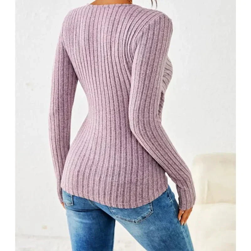 Mauve ribbed knit long-sleeve wrap top with side button detail and a fitted silhouette worn with blue jeans.