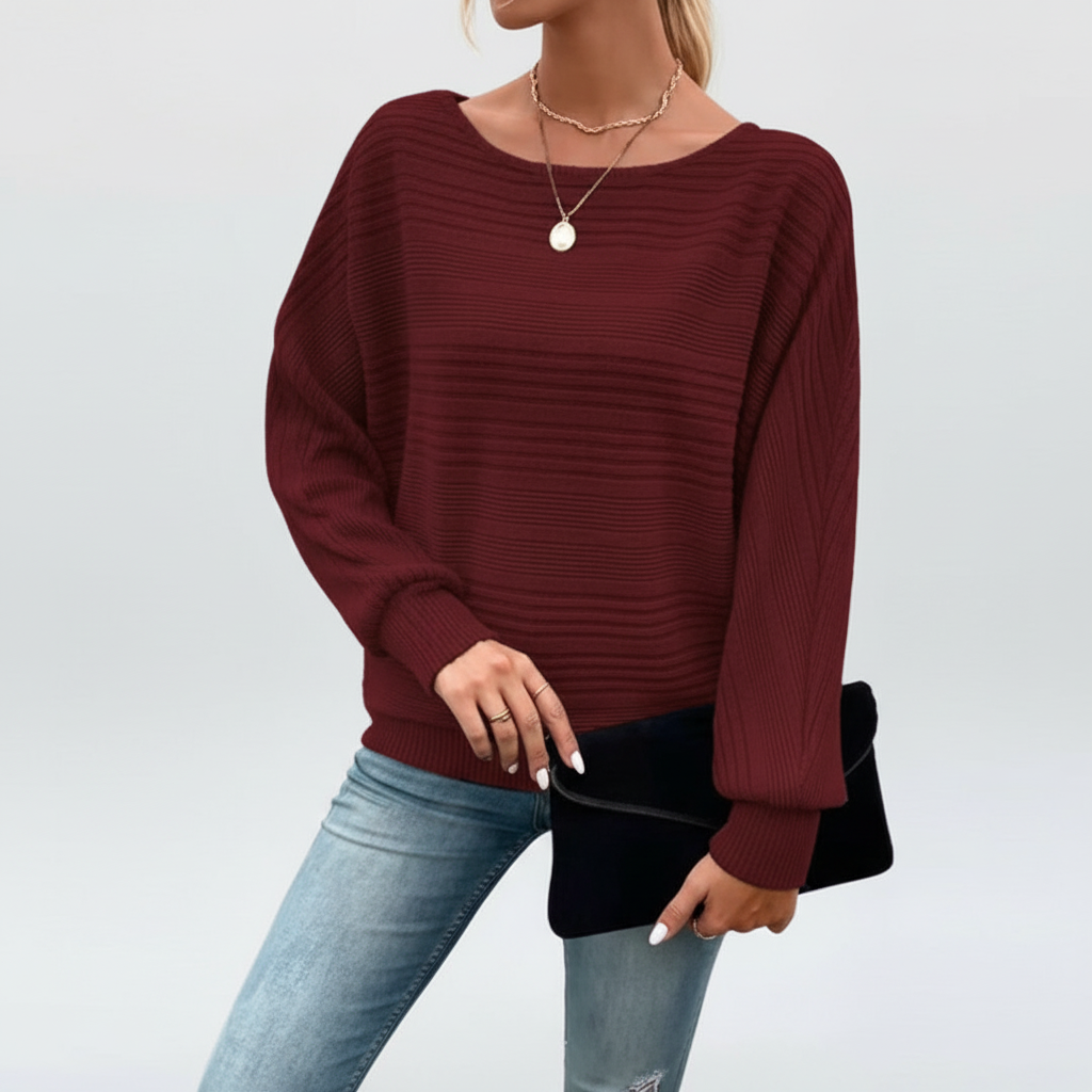 Wine red textured knit sweater with a wide round neckline, batwing sleeves, and ribbed cuffs worn with blue jeans.