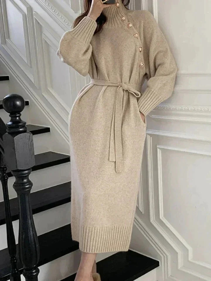 Beige turtleneck sweater dress with side buttons, long sleeves, and a tie waist, styled for autumn and winter.