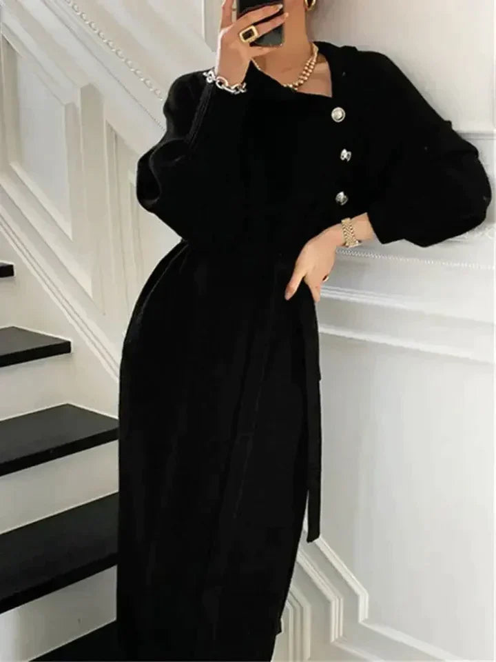 Elegant black sweater dress with a buttoned neckline, tie waist, and long sleeves, styled for a sophisticated winter look.