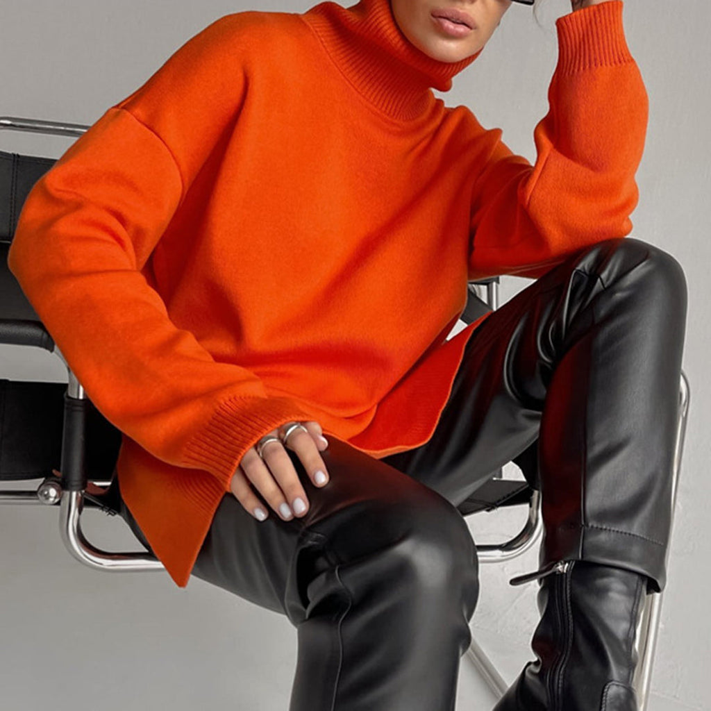 Bright orange relaxed-fit turtleneck sweater with long sleeves and side splits, paired with black leather trousers.