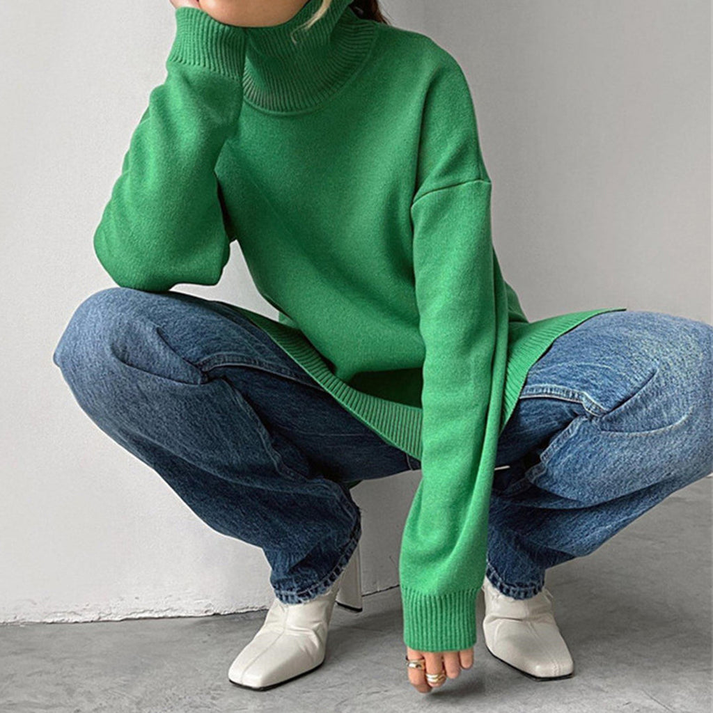 Bright green relaxed-fit turtleneck sweater with side splits, worn with blue jeans and white boots.