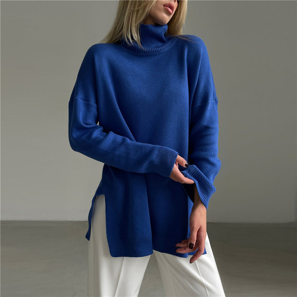 Relaxed-fit cobalt blue turtleneck sweater in soft knit with long sleeves and side splits, paired with white trousers.