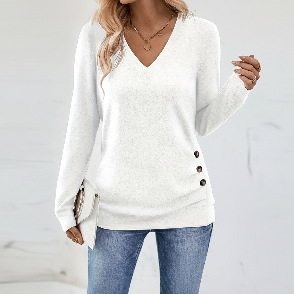 White long-sleeve V-neck sweater with side button detail and a relaxed fit, styled with blue denim jeans.