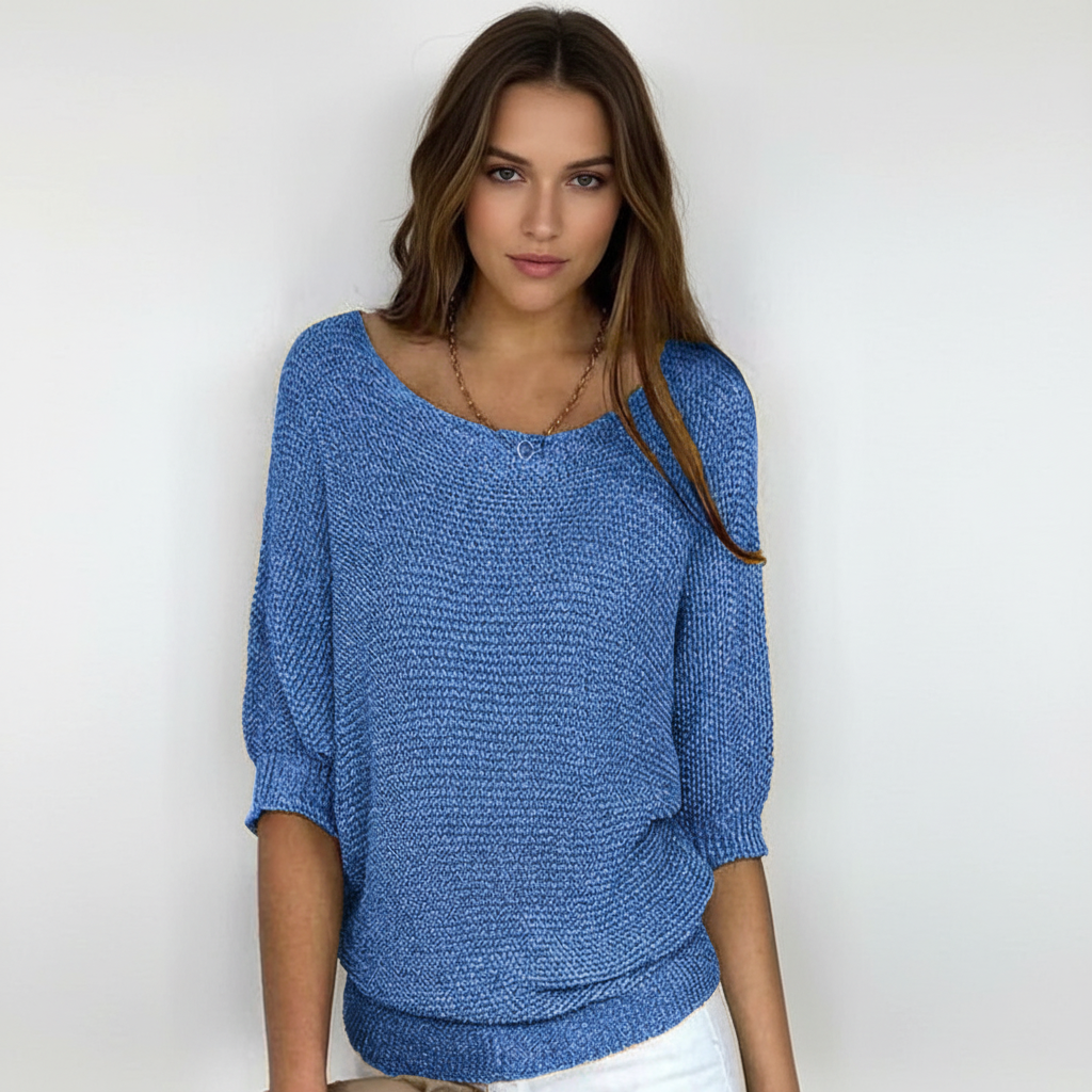 Blue relaxed-fit sweater with a wide neckline, dolman sleeves, and ribbed cuffs worn by a woman.