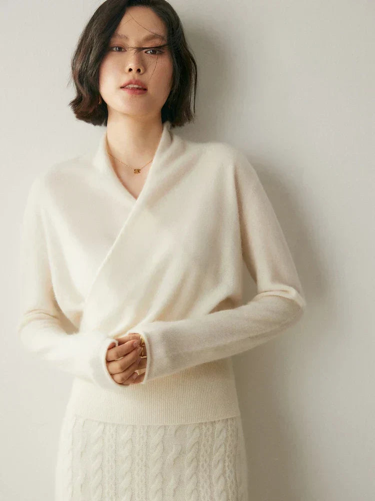 Woman wearing a white slim-fit knit sweater with a crossover wrap neckline and long sleeves with ribbed cuffs.