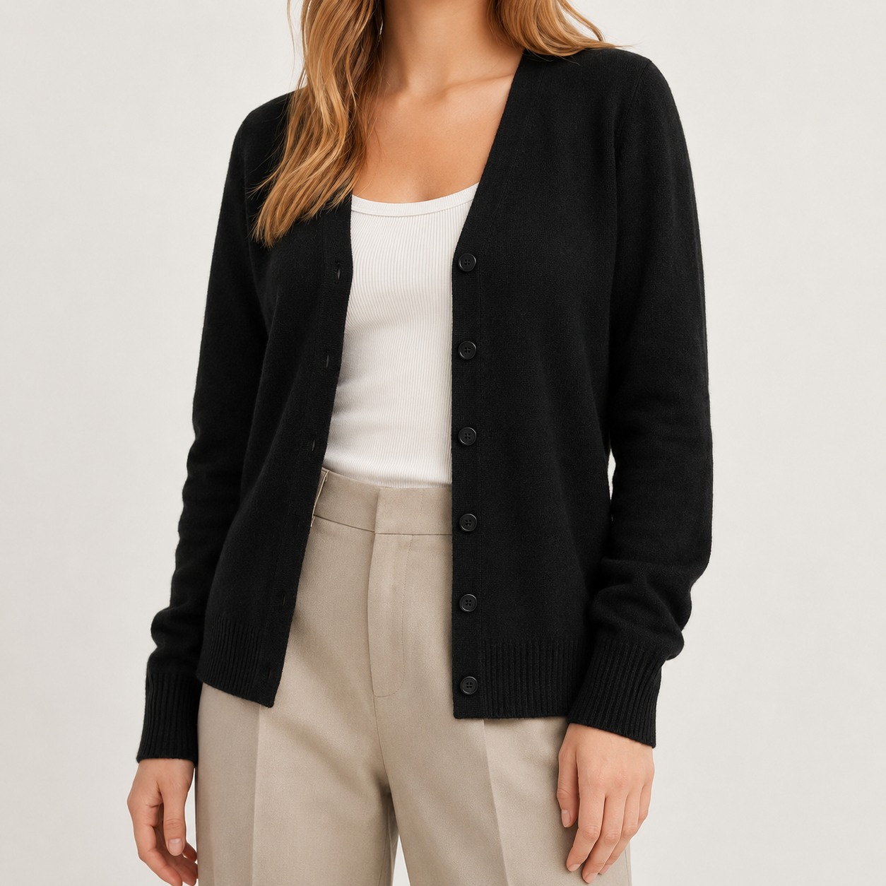 Black fine-knit V-neck cardigan with a button-front, long sleeves, and ribbed cuffs worn over a white top.
