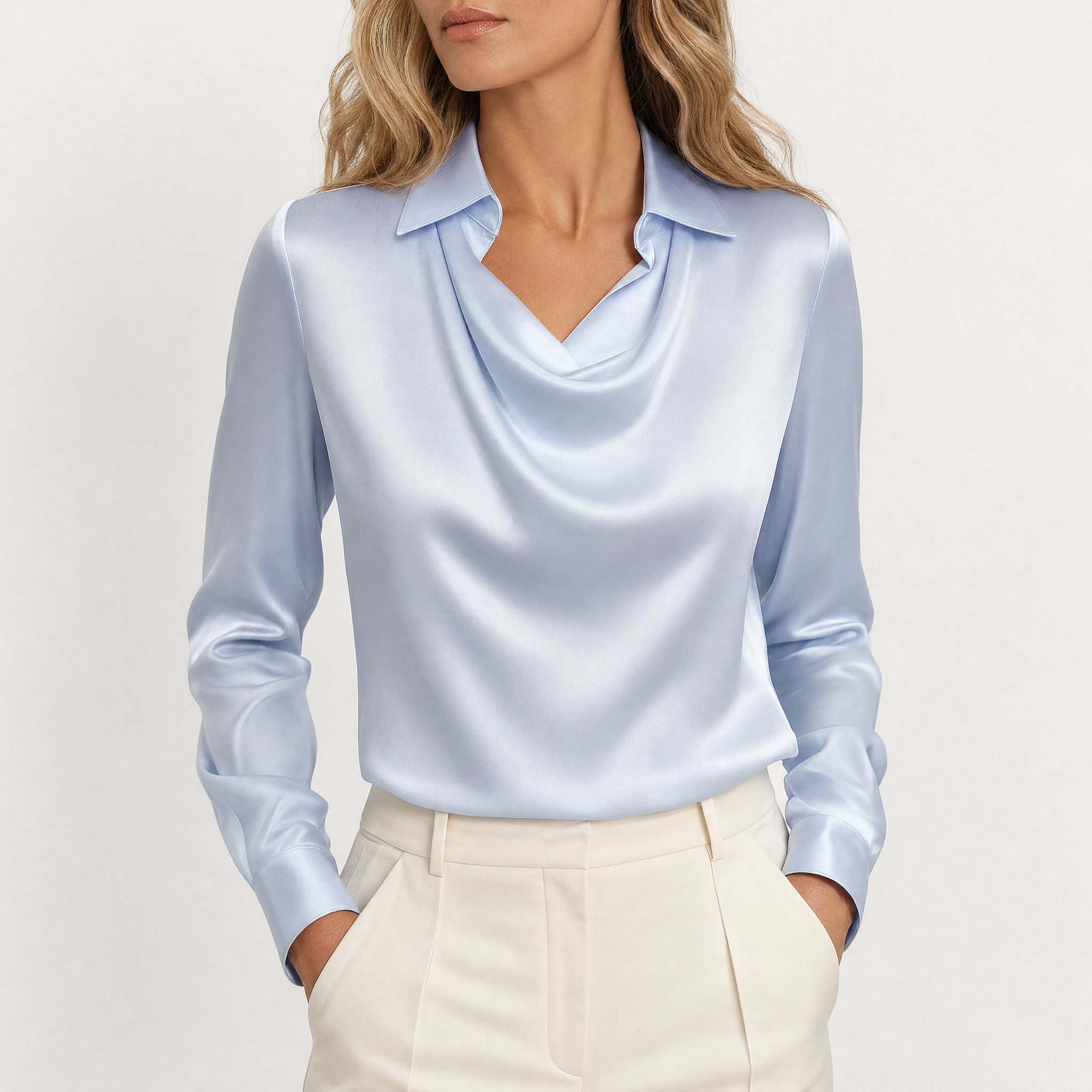 Model wearing blue draped neckline satin blouse with cream trousers