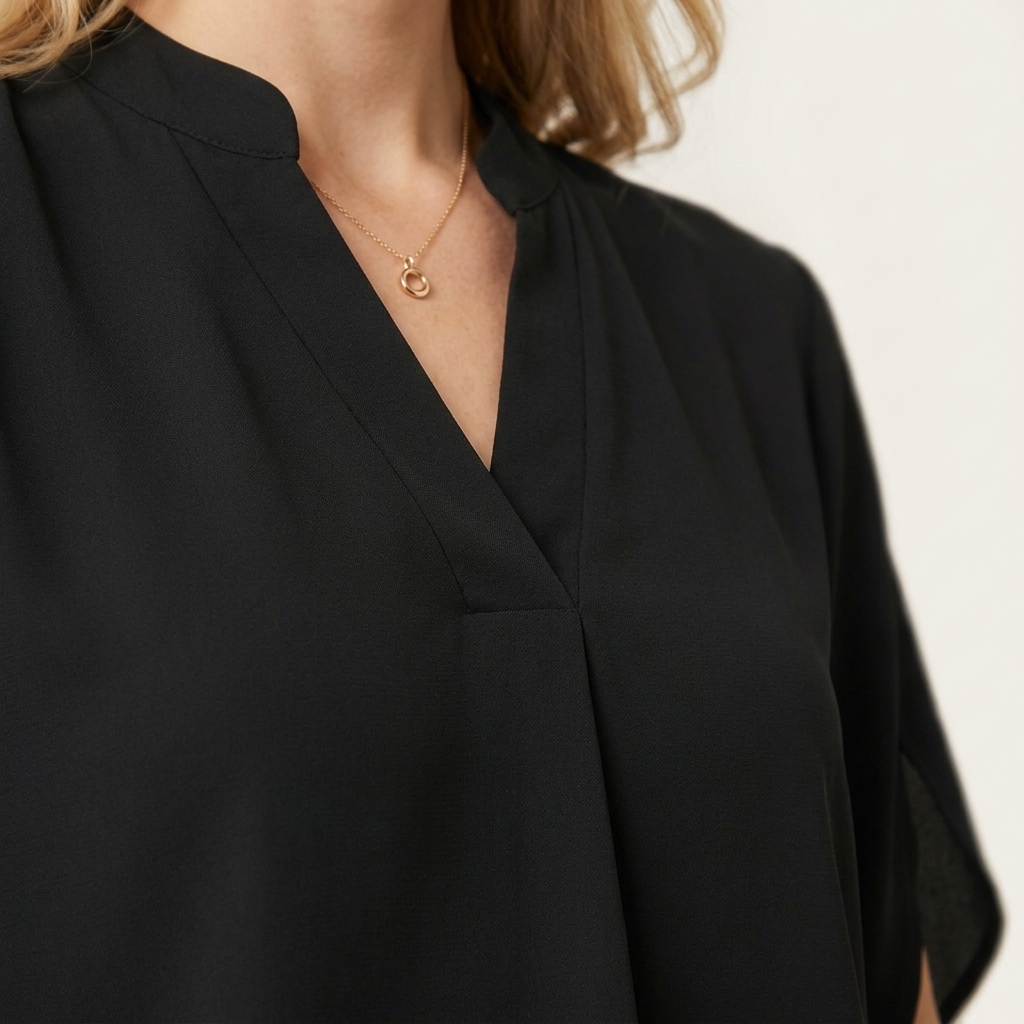 Close-up of the black blouse draped V-neckline detail