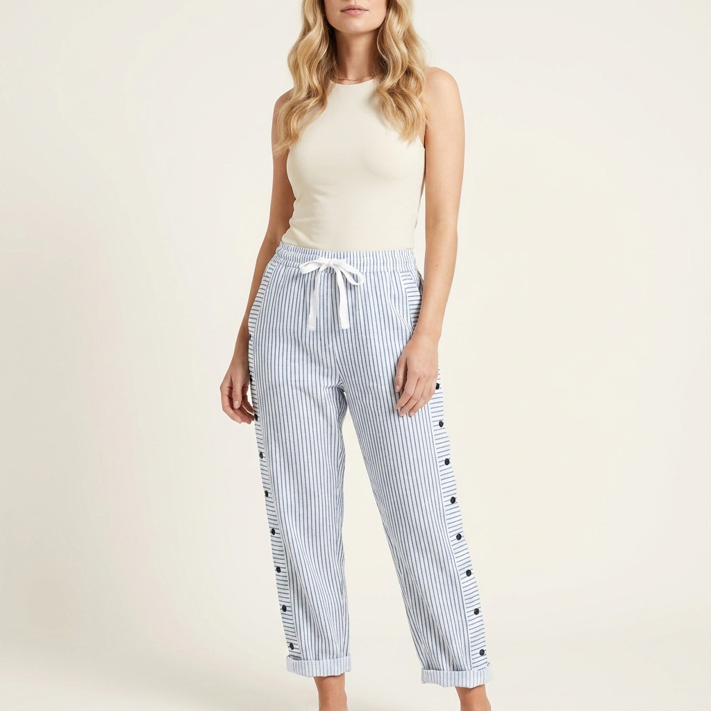 Woman wearing blue elasticated drawstring trousers with side button detail and rolled-up hem, front studio view