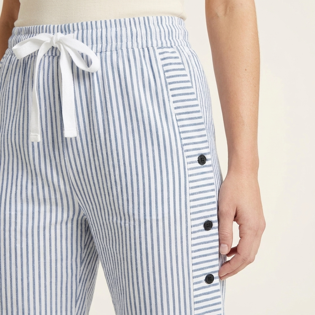 Close-up of the blue trousers waistband, drawstring and side button detail